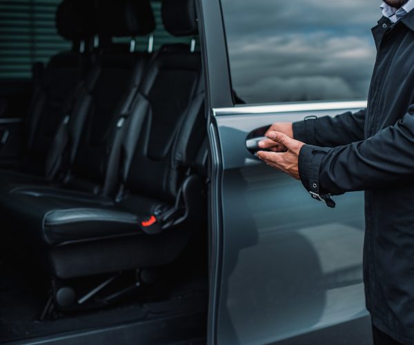 The personal driver welcoming you in the luxury transfer car.
